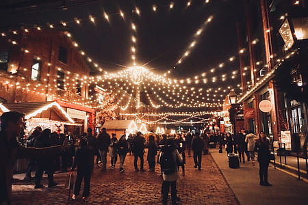 group of people walking on street under yellow string lights thumbnail