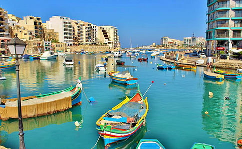 assorted-color boats floating on body of water beside buildings at daytime thumbnail