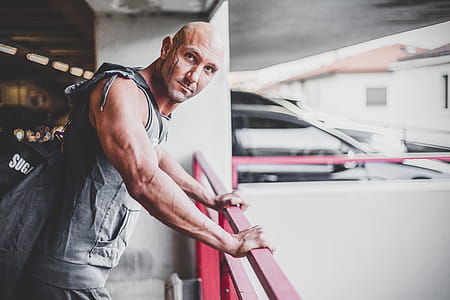 Man Wearing Gray Apron Placing His Hands on Red Metal Handrail thumbnail