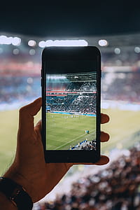 focus photography of person taking photo of soccer players using iPhone thumbnail