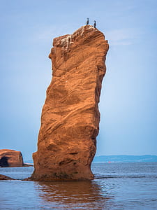 rock formation on body of water under blue sky thumbnail