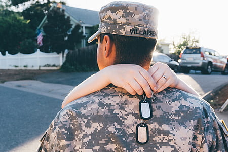 person's arms holding dog tags on man's shoulder standing during daytime thumbnail