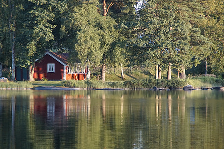 brown barn beside lake during daytime thumbnail