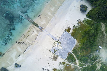 aerial photography of beach and blue ocean water surrounded by green leafed trees during daytime thumbnail