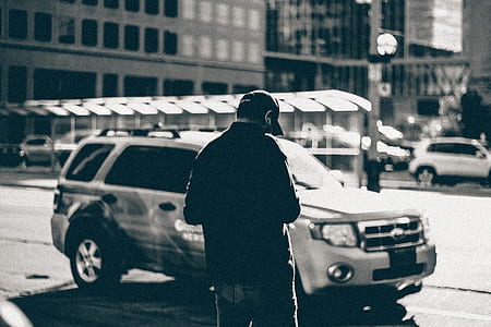 Grayscale Photography of Man Standing Near Suv during Daytime thumbnail