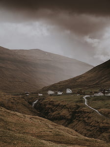 houses near mountain under cloudy sky at daytime thumbnail