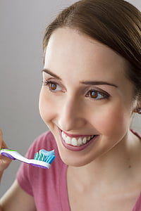woman holding toothbrush while smiling thumbnail