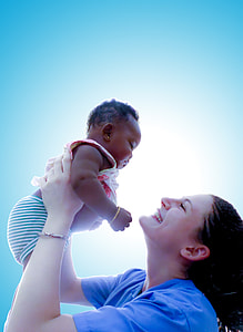 mother in purple crew-neck t-shirt rising her baby up while smiling at her during daytime thumbnail