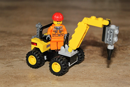 close-up photography of minifig with red hat standing on yellow and black heavy equipment minifig toy thumbnail