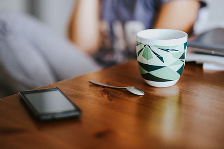 Laptop, a smartphone, magazines and cups of coffee on a table thumbnail