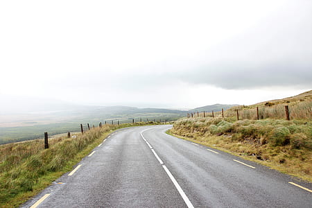 landscape photography of freeway between green grasses during daytime thumbnail