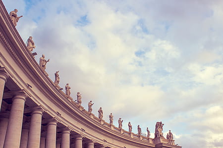 Gray Concrete Building With Human Statues Under Cloudy Sky thumbnail
