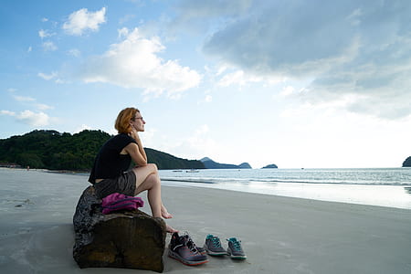 woman sitting on brown log in front seashore thumbnail