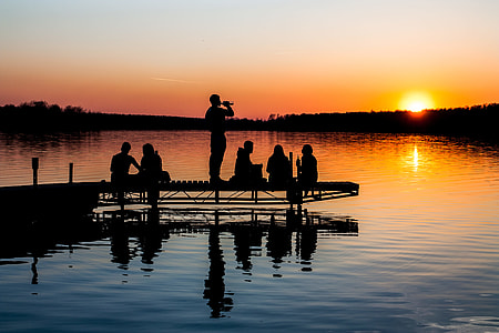 silhouette of six people on brown wooden dock near lake thumbnail