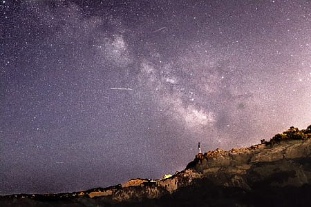 person standing on mountain under starry night thumbnail