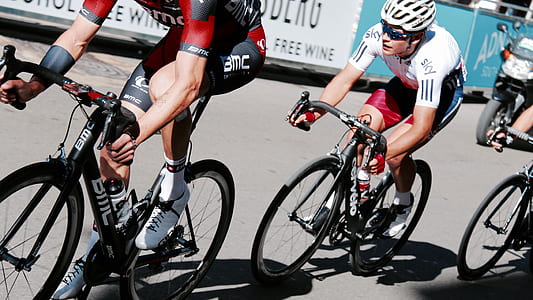 man riding black road bike behind another man during daytime thumbnail