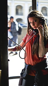 Woman in Red T-shirt Holding Telephone Inside Telephone Booth thumbnail