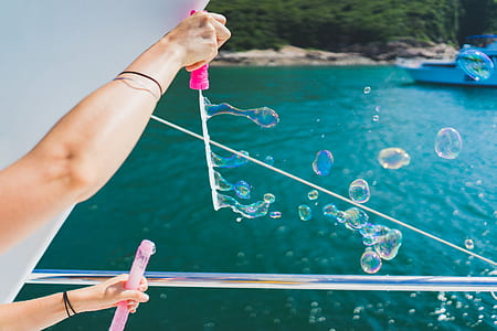 person playing bubbles near body of water thumbnail