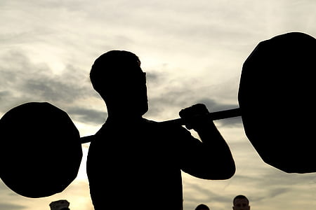 silhouette photography of man holding barbel thumbnail