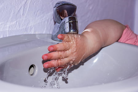 child washing right hand on white ceramic sink thumbnail