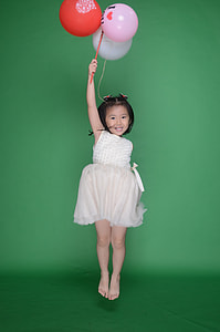 girl in white sleeveless dress holding red, white, and pink balloons thumbnail