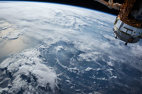 white and gray spacecraft facing earth planet thumbnail