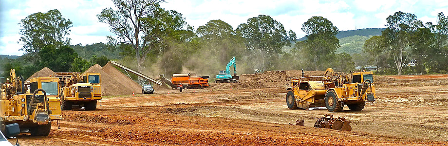 yellow heavy equipment on brown field thumbnail