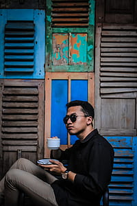 man about to drink on teacup while sitting on chair thumbnail