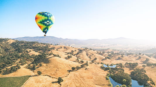 green, red, and teal hot air balloon above hills thumbnail