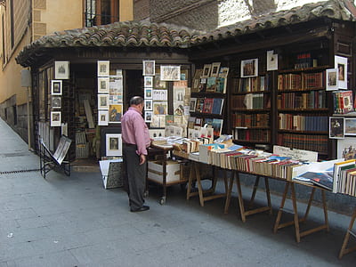 man standing beside book lot during daytime thumbnail