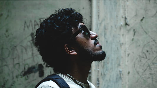 man wearing sunglasses looking up near wall thumbnail