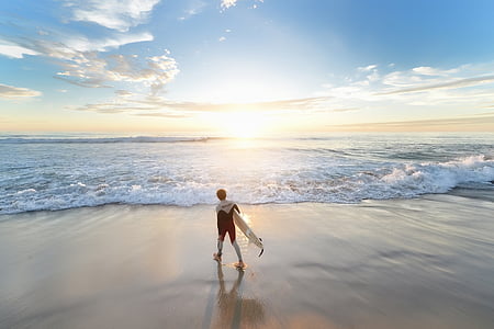 man carrying surfboard walking on shore thumbnail
