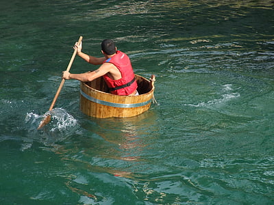 man on brown wooden boat holding a paddle thumbnail
