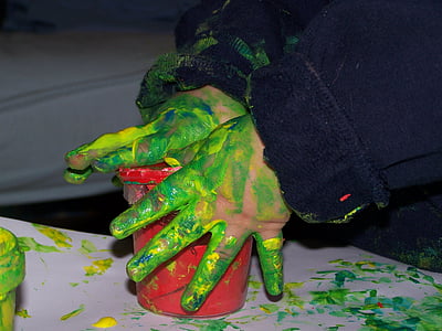 person in black jacket holding red plastic container with paint on hand thumbnail