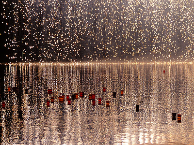 red and black floating candles on body of water thumbnail
