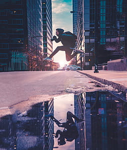 man jumping over gray concrete road mirrored on calm body of water during golden hour thumbnail