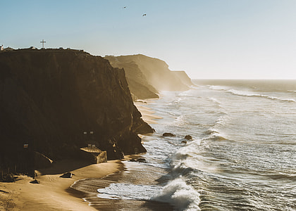 brown mountain beside blue sea during daytime thumbnail