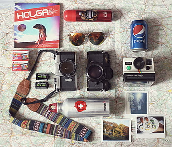 three camera, bottles, and pictures on white map surface thumbnail
