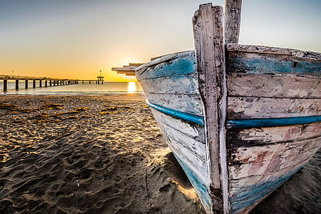 gray and green punt boat beside beach thumbnail