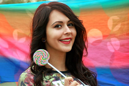 woman wearing green and brown camouflage shirt holding swirl lollipop thumbnail