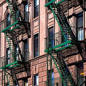 green metal fire exit ladder on beige concrete building thumbnail