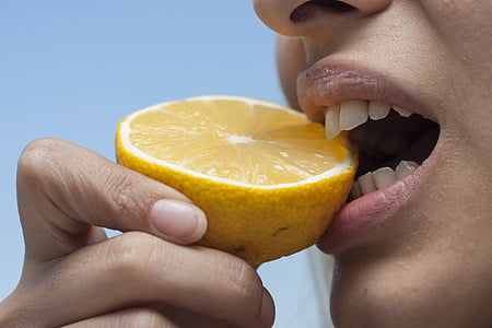 close photo of person biting yellow citrus fruit thumbnail