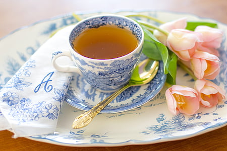 teacup on saucer beside pink flowers thumbnail