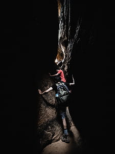man in black shirt walking in the middle of the rock formation thumbnail