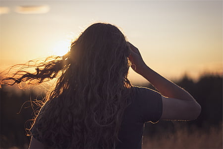 woman standing with right hand near face facing sun thumbnail