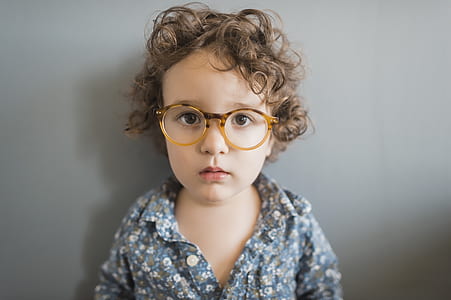 girl's blue and white floral collared button-up shirt leaning on gray wall thumbnail