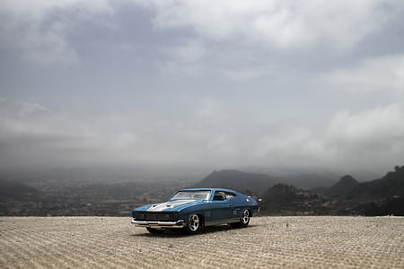 classic blue and white coupe parked under gray sky thumbnail