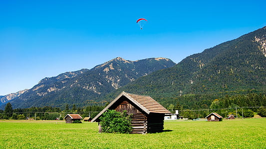 Brown Wooden House on Grass Field Near Mountain thumbnail