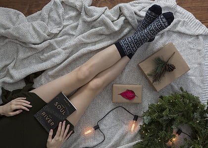 person sitting beside string lights and wreath holding book thumbnail