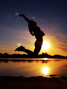 silhouette of woman jumps during sunset thumbnail